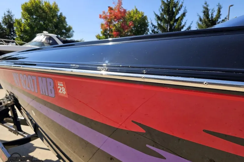 Slide: The Image of 2005 Baja 25 Outlaw boat with red and black exterior, parked outdoors. - 26