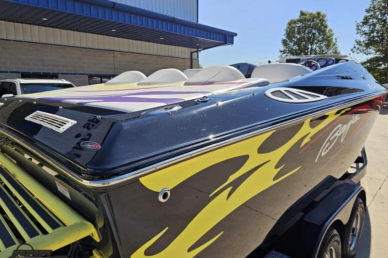 Slide: The Image of 2005 Baja 25 Outlaw speedboat with vibrant flame graphics, parked outdoors. - 38