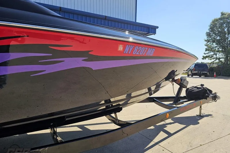 Slide: The Image of 2005 Baja 25 Outlaw boat on trailer with vibrant red and purple graphics. - 4