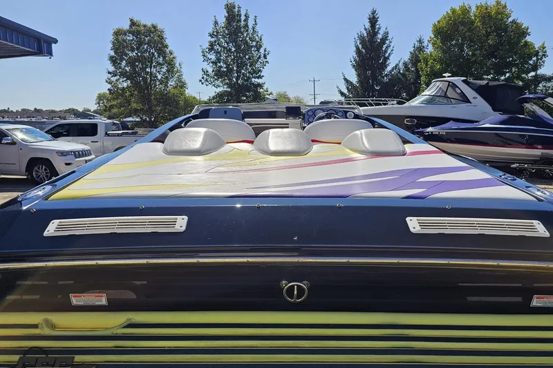 Slide: The Image of 2005 Baja 25 Outlaw boat with colorful deck design, parked outdoors. - 40