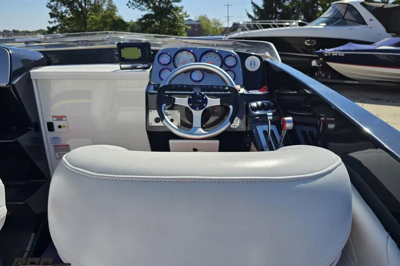 Slide: The Image of 2005 Baja 25 Outlaw boat cockpit with steering wheel and gauges, docked near other boats. - 57