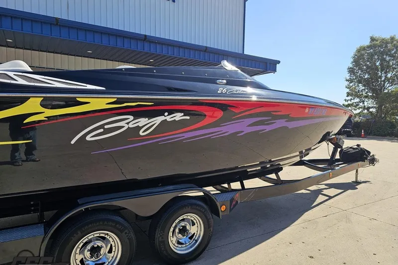 Slide: The Image of 2005 Baja 25 Outlaw speedboat with vibrant graphics on a trailer. - 6