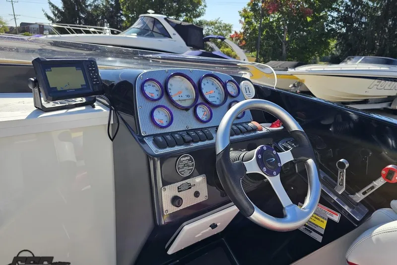 Slide: The Image of 2005 Baja 25 Outlaw boat dashboard with steering wheel and gauges in a marina setting. - 67