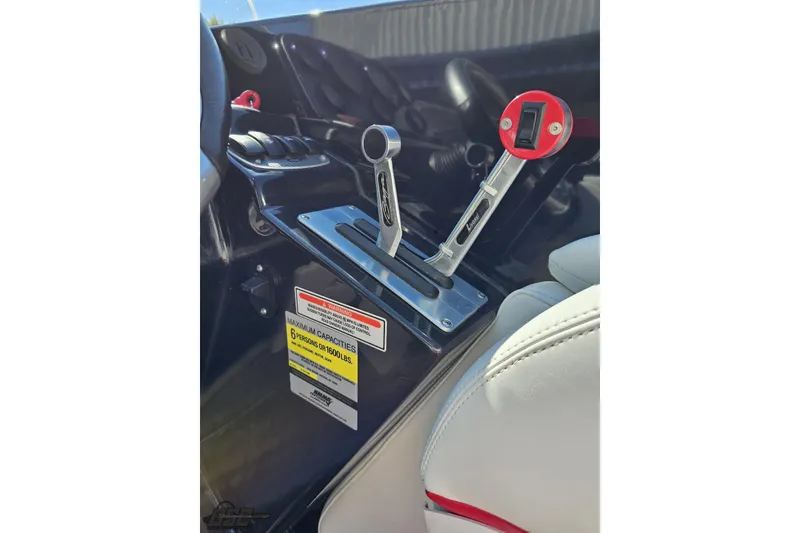 Slide: The Image of 2005 Baja 25 Outlaw boat controls with red throttle levers and capacity warning label. - 69