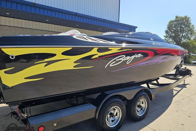 Slide: The Image of 2005 Baja 25 Outlaw speedboat with vibrant flame graphics on a trailer. - 7