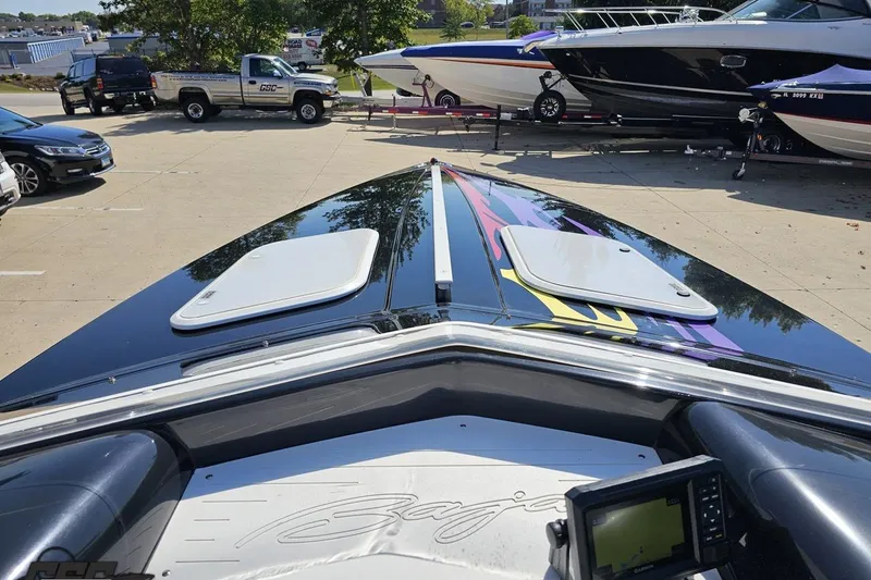 Slide: The Image of 2005 Baja 25 Outlaw boat with vibrant graphics, parked in a marina lot. - 72