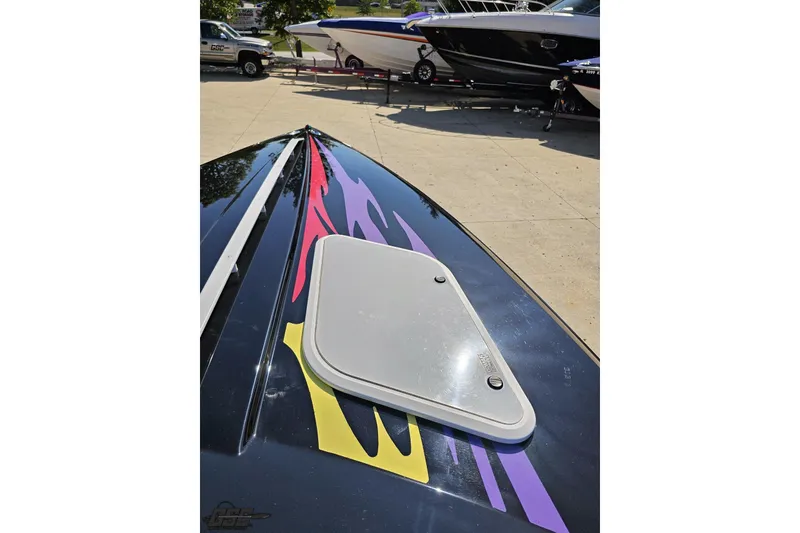 Slide: The Image of 2005 Baja 25 Outlaw boat with vibrant graphics on deck, parked outdoors. - 74
