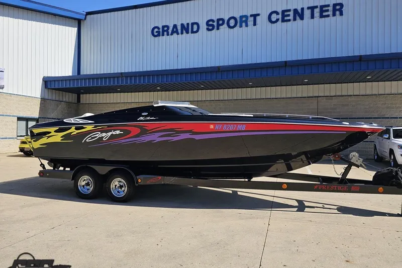Slide: The Image of 2005 Baja 25 Outlaw speedboat with vibrant graphics on a trailer at Grand Sport Center. - 9