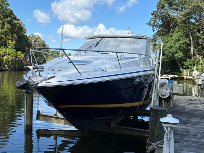 The Image of 2016 Regal 35 Sport Coupe docked on a sunny day, surrounded by lush greenery. - 0