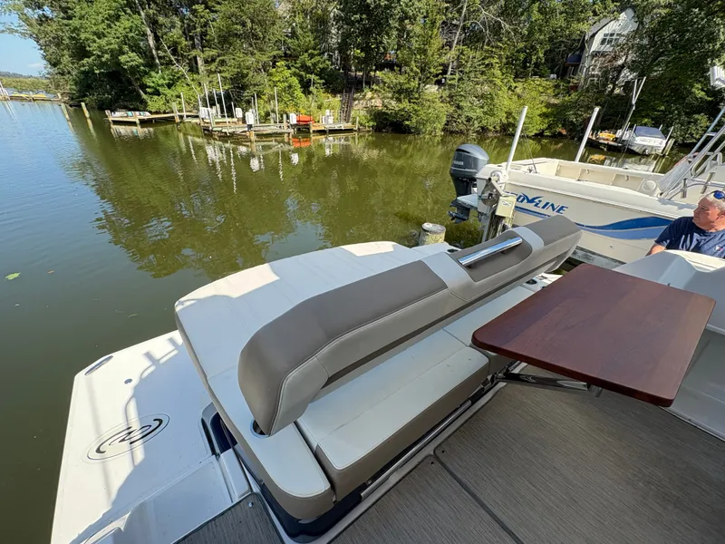 Slide: The Image of 2016 Regal 35 Sport Coupe boat with seating and table, docked by a serene lake. - 11