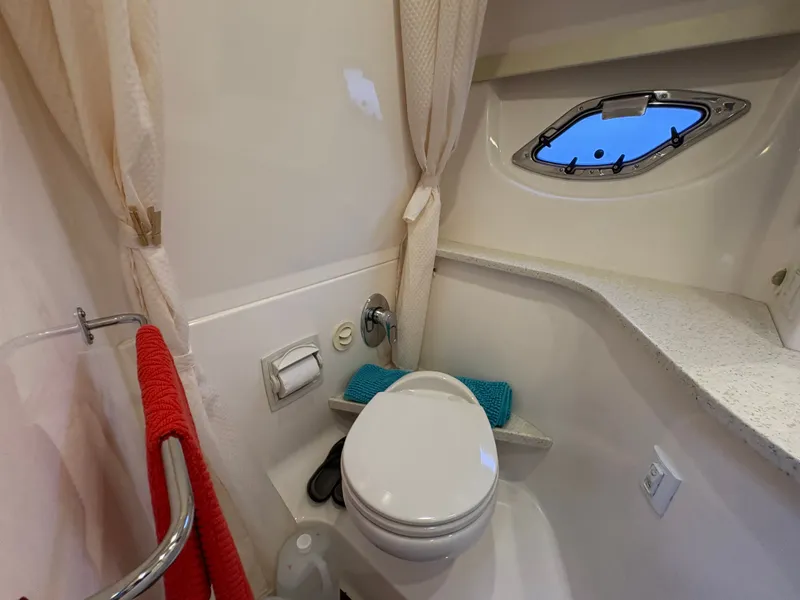 Slide: The Image of 2016 Regal 35 Sport Coupe bathroom with toilet, porthole, and red towel. - 49
