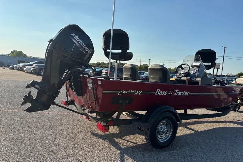 Slide: The Image of 2024 Bass Tracker XL boat with windshield, parked near a warehouse. - 15
