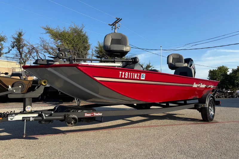 Slide: The Image of 2024 Bass Tracker XL boat with Mercury engine, red exterior, parked on trailer. - 2