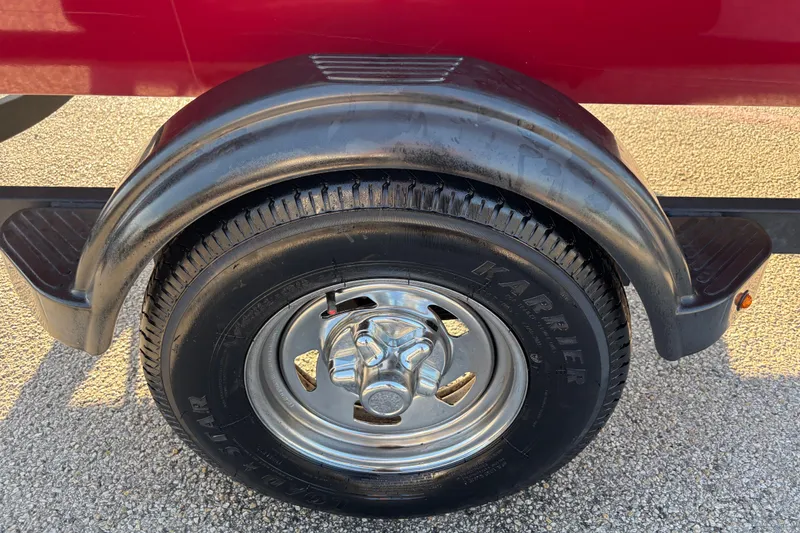 Slide: The Image of 2024 Bass Tracker XL trailer wheel with black fender and chrome rim on asphalt. - 34