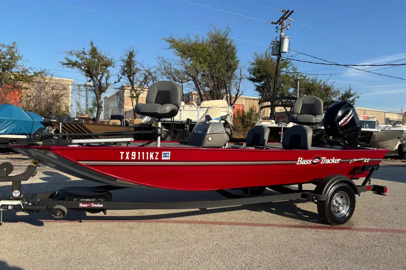 Slide: The Image of 2024 Bass Tracker XL boat in vibrant red on a trailer, parked outdoors. - 4