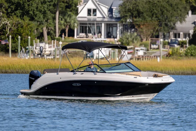 Slide: The Image of 2019 Sea Ray SDX 250 Outboard cruising on a serene waterway near waterfront homes. - 33