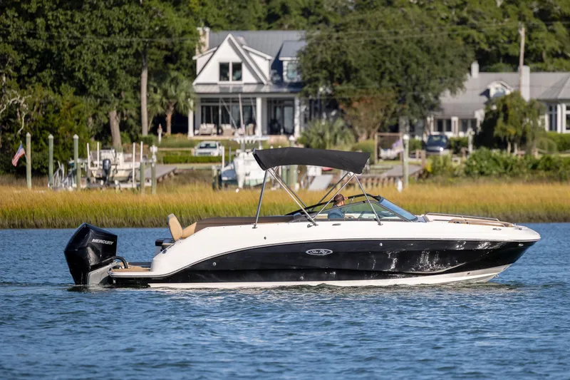 Slide: The Image of 2019 Sea Ray SDX 250 Outboard boat cruising on a serene lake near waterfront homes. - 34