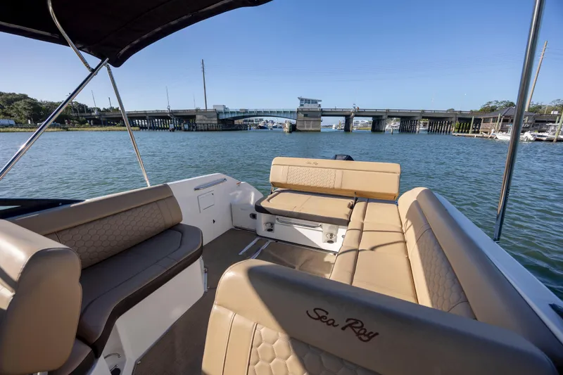 Slide: The Image of 2019 Sea Ray SDX 250 Outboard boat interior with tan seating, overlooking a bridge and waterway. - 42