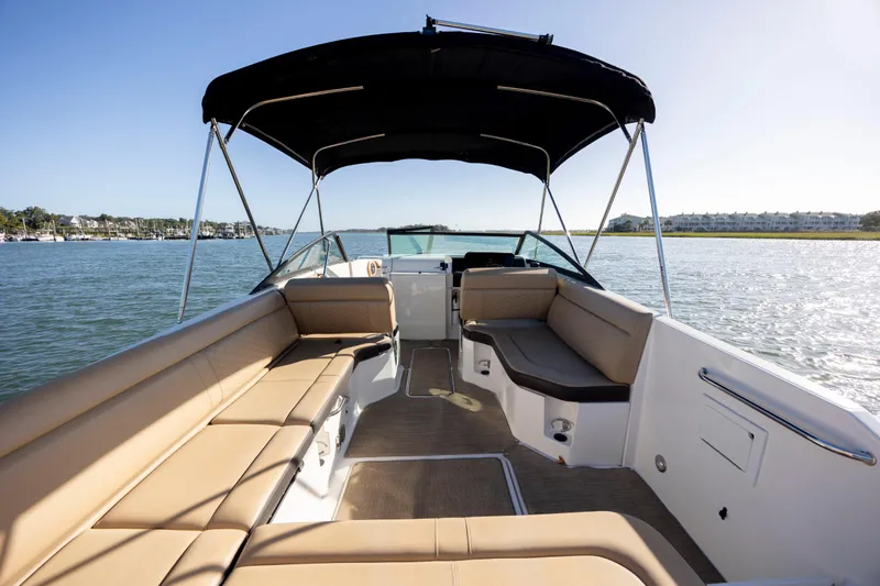 Slide: The Image of 2019 Sea Ray SDX 250 Outboard boat interior with tan seating and canopy on calm water. - 44
