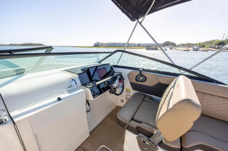 Slide: The Image of 2019 Sea Ray SDX 250 Outboard cockpit with steering wheel and seating, overlooking water. - 46