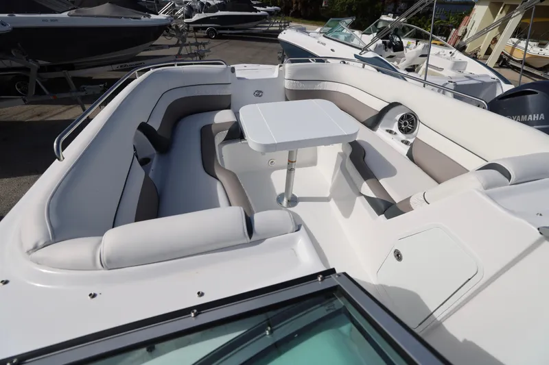 Slide: The Image of 2026 Hurricane SunDeck 2486 OB boat interior with seating and table, docked among other boats. - 18