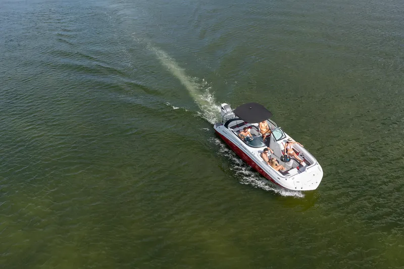Slide: The Image of 2026 Hurricane SunDeck 2486 OB boat on trailer, parked outdoors under clear blue sky. - 24