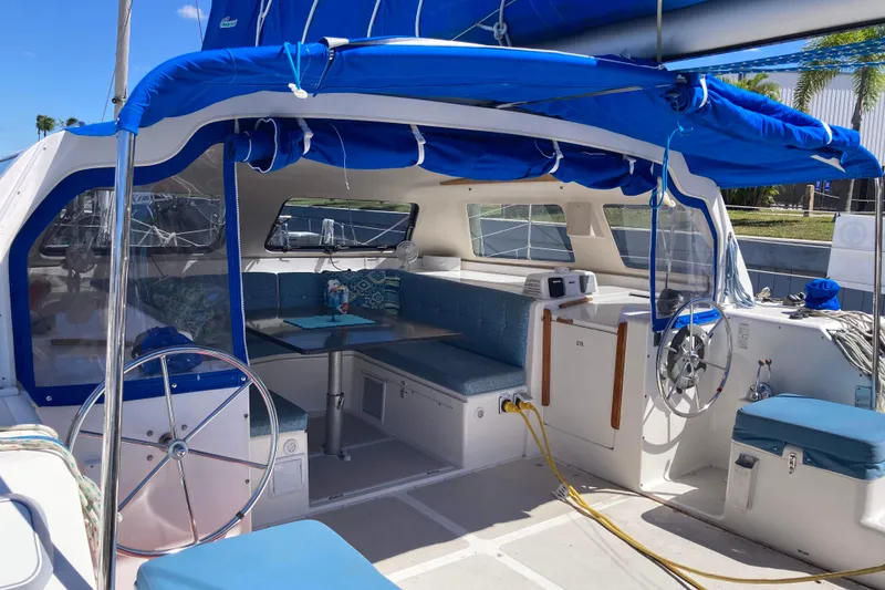 Slide: The Image of 2009 Seawind 36 1000XL catamaran interior with blue seating and helm, docked under sunny skies. - 15