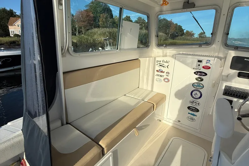 Slide: The Image of Interior of 2014 Steiger Craft 26' Miami boat with cushioned seating and window view. - 14