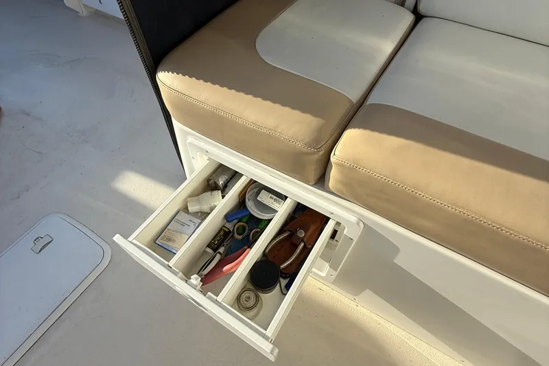 Slide: The Image of 2014 Steiger Craft 26' Miami boat interior with open storage drawer under beige seating. - 15