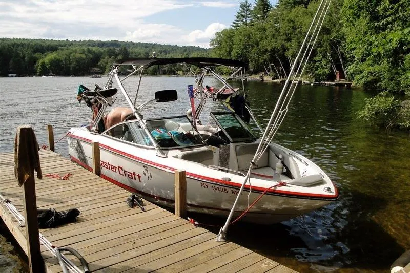Slide: The Image of 2009 MasterCraft X-15 boat docked on a serene lake with lush greenery. - 2
