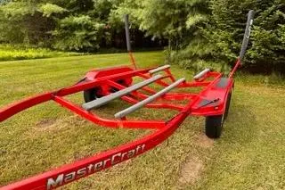 Slide: The Image of Red 2009 MasterCraft X-15 boat trailer on grass, surrounded by trees. - 20