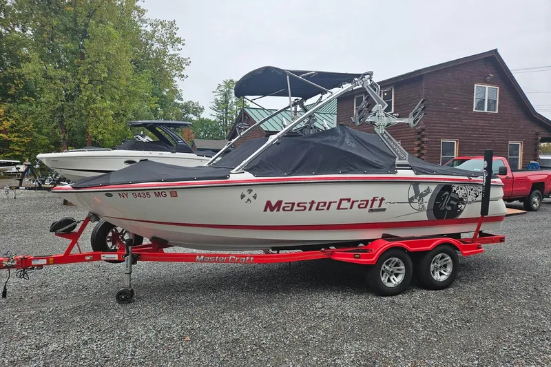 Slide: The Image of 2009 MasterCraft X-15 boat on red trailer, parked outdoors near wooden building. - 3
