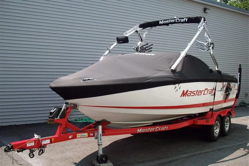 Slide: The Image of 2009 MasterCraft X-15 boat on red trailer, covered and parked outdoors. - 4