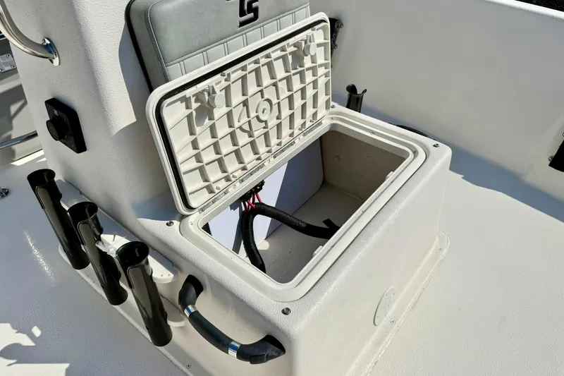 Slide: The Image of 2025 Carolina Skiff EV198 Sea Skiff storage compartment with open lid and rod holders. - 15