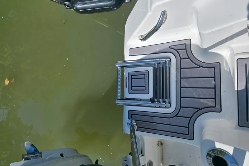 Slide: The Image of 2024 Tidewater 220 CC Adventure boat with swim platform and ladder in water. - 10