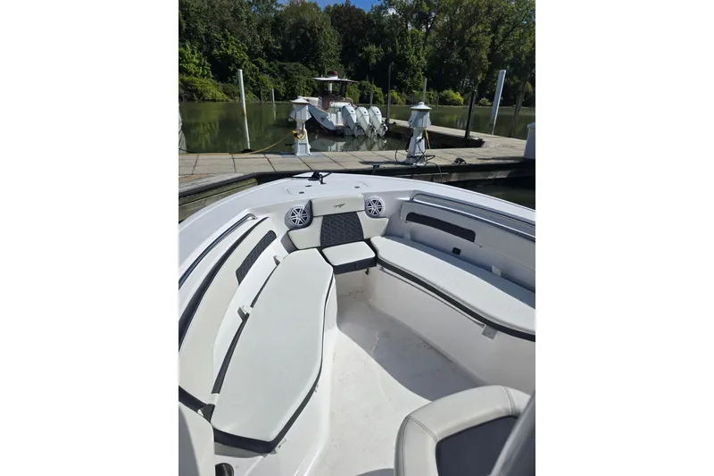 Slide: The Image of 2024 Tidewater 220 CC Adventure boat interior with seating, docked near lush greenery. - 11