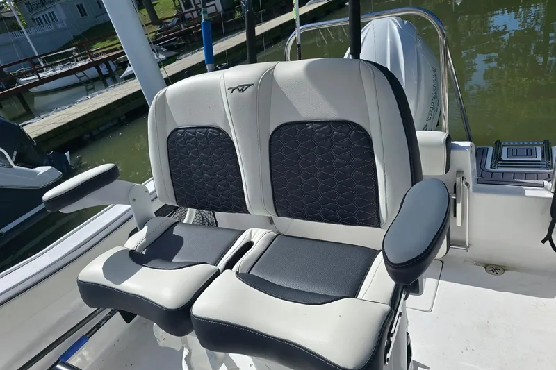 Slide: The Image of 2024 Tidewater 220 CC Adventure boat seats with black and white upholstery, dockside view. - 13