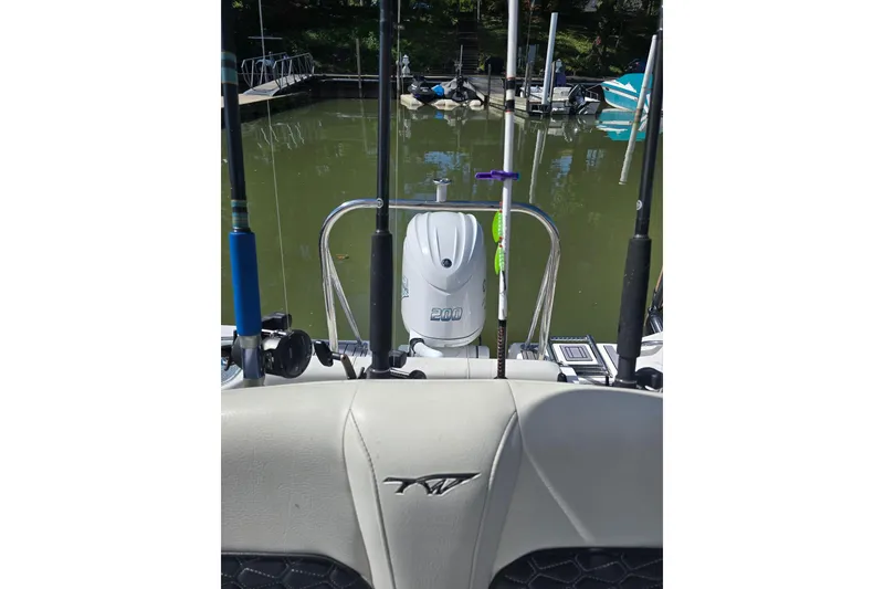 Slide: The Image of 2024 Tidewater 220 CC Adventure boat with fishing rods and motor at dock. - 14