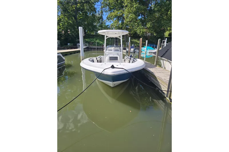 Slide: The Image of 2024 Tidewater 220 CC Adventure boat docked in a serene marina setting. - 2