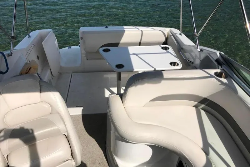Slide: The Image of 2005 Chaparral Signature 260 boat interior with white seating and table on clear water. - 10