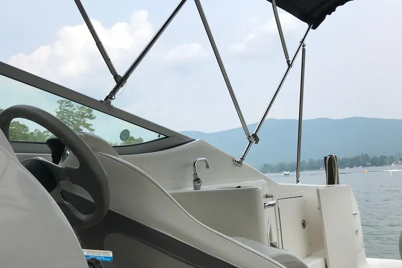 Slide: The Image of 2005 Chaparral Signature 260 boat interior with steering wheel, lake view, and mountains in background. - 16