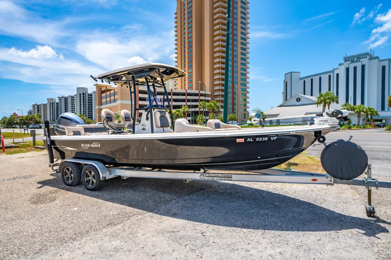 Slide: The Image of 2020 Blue Wave 2400 PureBay boat on trailer, urban background, sunny day. - 2