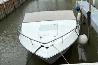 Slide: The Image of 1991 Wellcraft 216 Eclipse boat docked in a marina, covered and secured with ropes. - 2