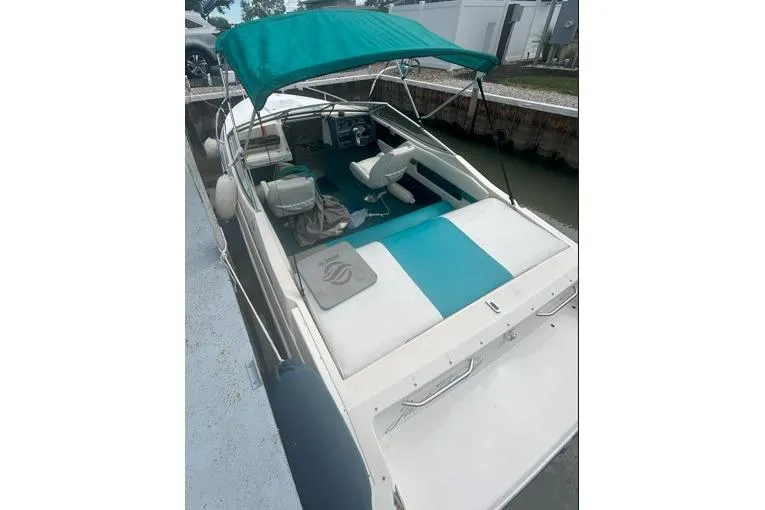 Slide: The Image of 1991 Wellcraft 216 Eclipse boat with teal canopy and seating, docked at marina. - 3