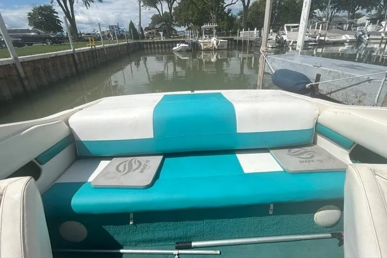 Slide: The Image of 1991 Wellcraft 216 Eclipse boat interior with teal and white seating at a marina. - 6