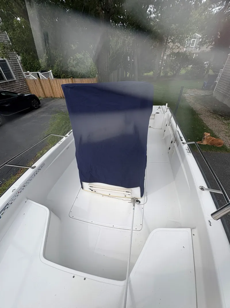 Slide: The Image of 2004 Boston Whaler 220 Dauntless boat interior with blue cover, parked in driveway. - 10
