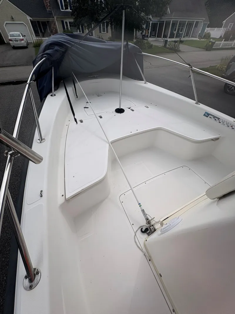 Slide: The Image of 2004 Boston Whaler 220 Dauntless boat interior with seating and railing, parked in residential area. - 6