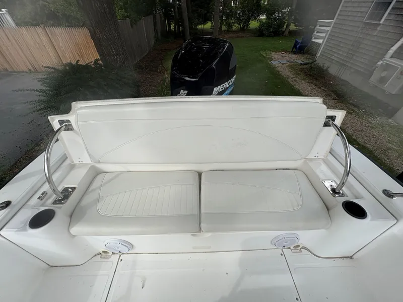 Slide: The Image of Boston Whaler 220 Dauntless 2004 boat seating area with white cushions and cup holders. - 9