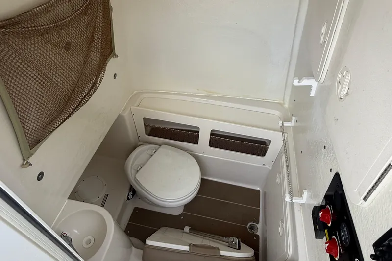 Slide: The Image of 2019 Sailfish 270 CC boat interior with compact marine toilet and storage net. - 14