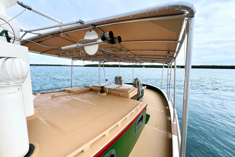 Slide: The Image of 1972 Mills Boat Works Tug Boat on calm water, featuring a covered deck. - 11